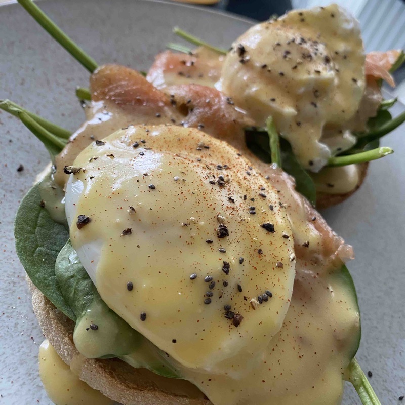 Salmon, spinach, poached egg, topped with hollandaise sauce, on a muffin