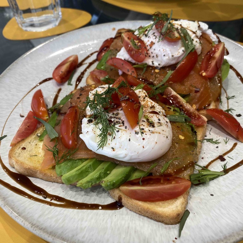 Salmon, avocado, poached egg and cherry tomatoes on toast, topped with dill, paprika, and chia seeds